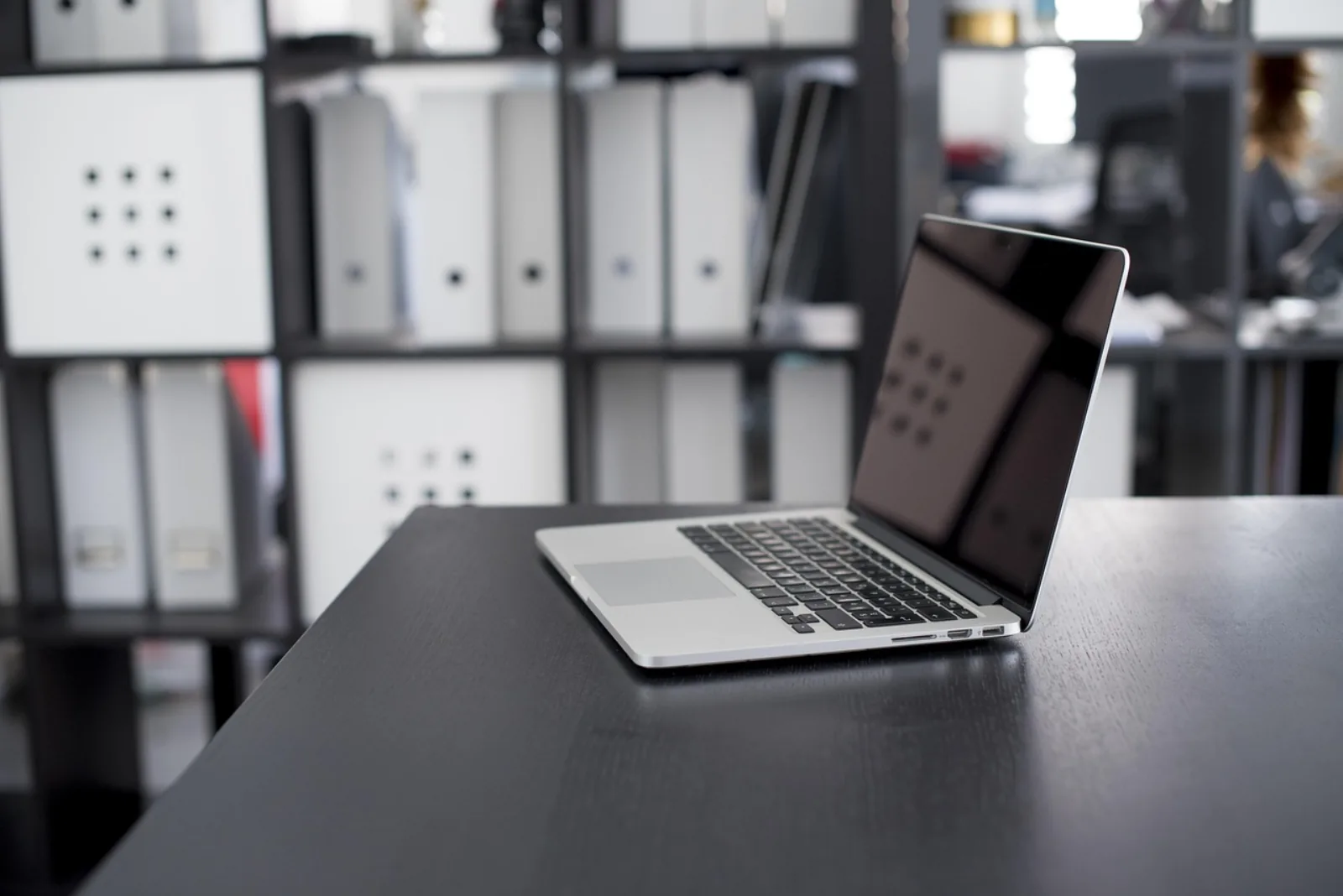 Laptop auf einem Schreibtisch vor Aktenregalen – Sinnbild für IT-Asset-Management im KMU
