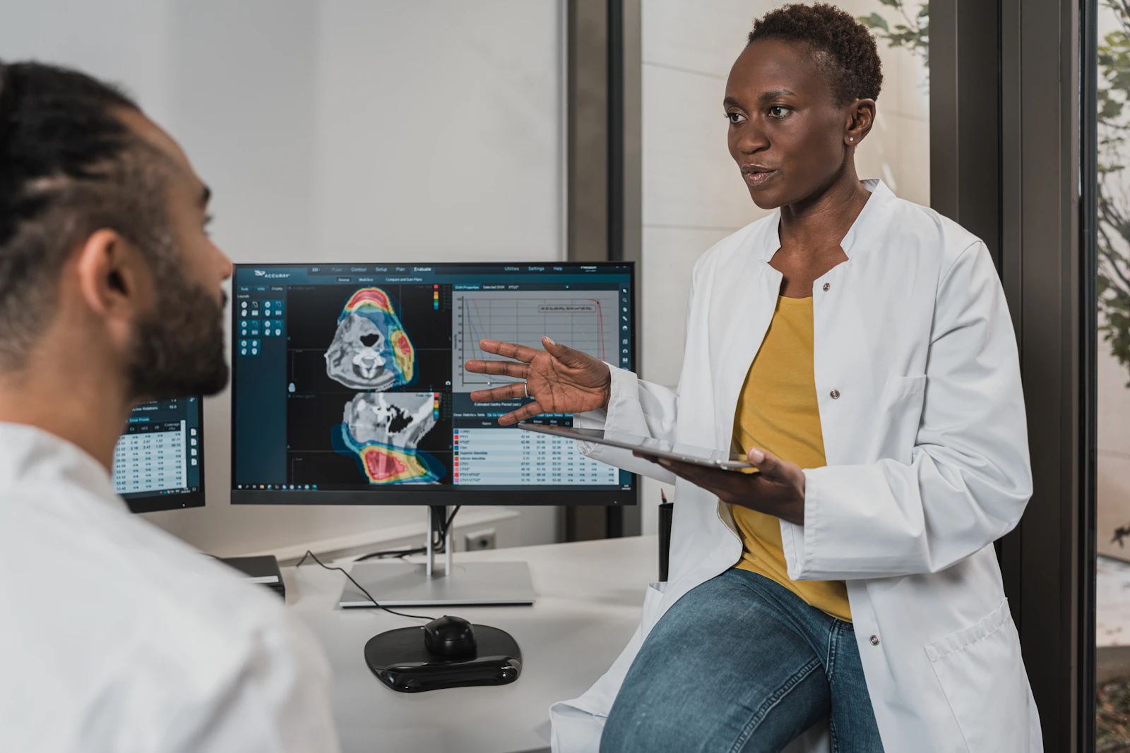 Ärztin bespricht mit einem Patienten Befunde am Bildschirm in einer modernen Praxis